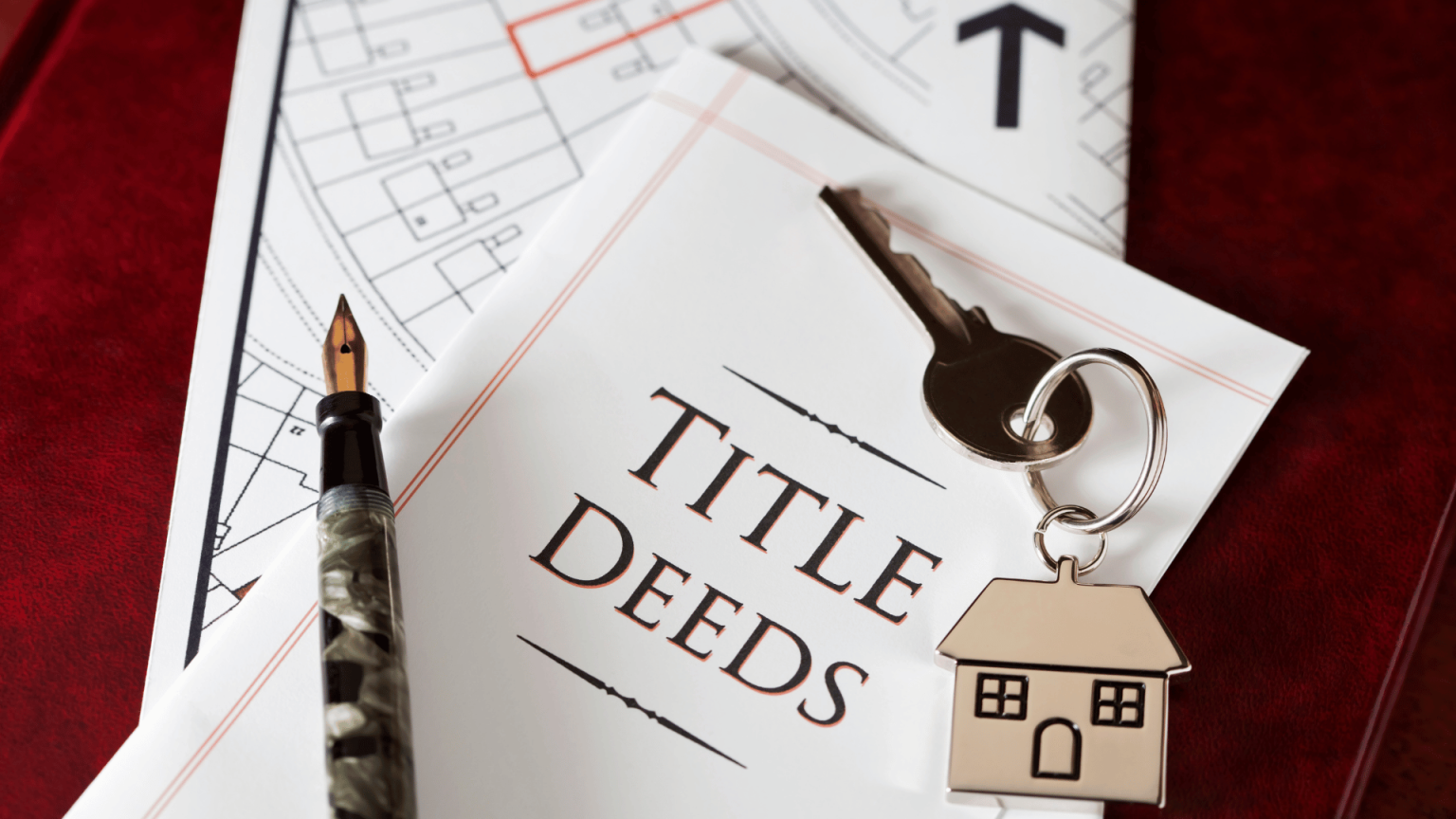 House keys and a pen resting on real estate title deeds paperwork for a property transfer.