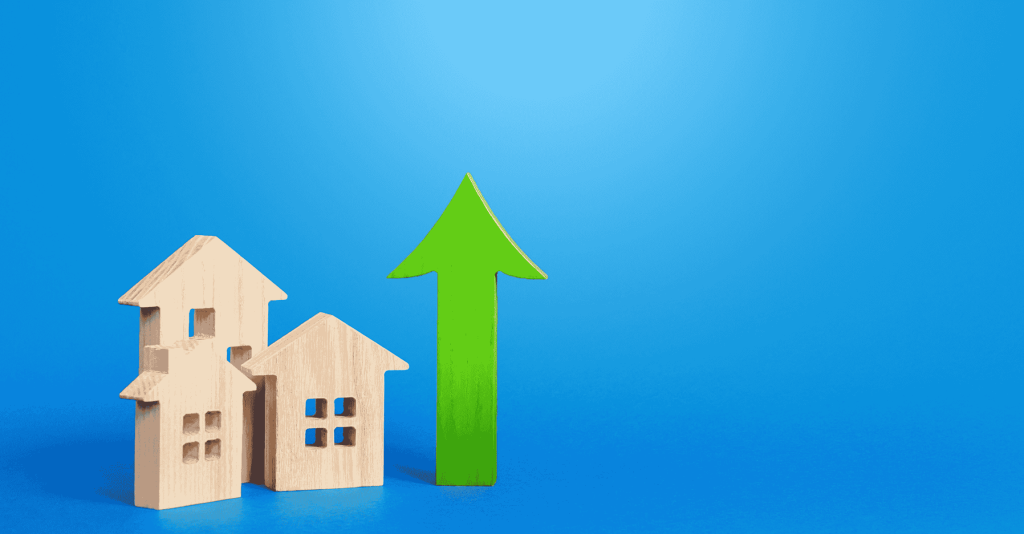 Wooden house models with a green upward arrow on a blue background, symbolizing rising mortgage applications and housing market growth.