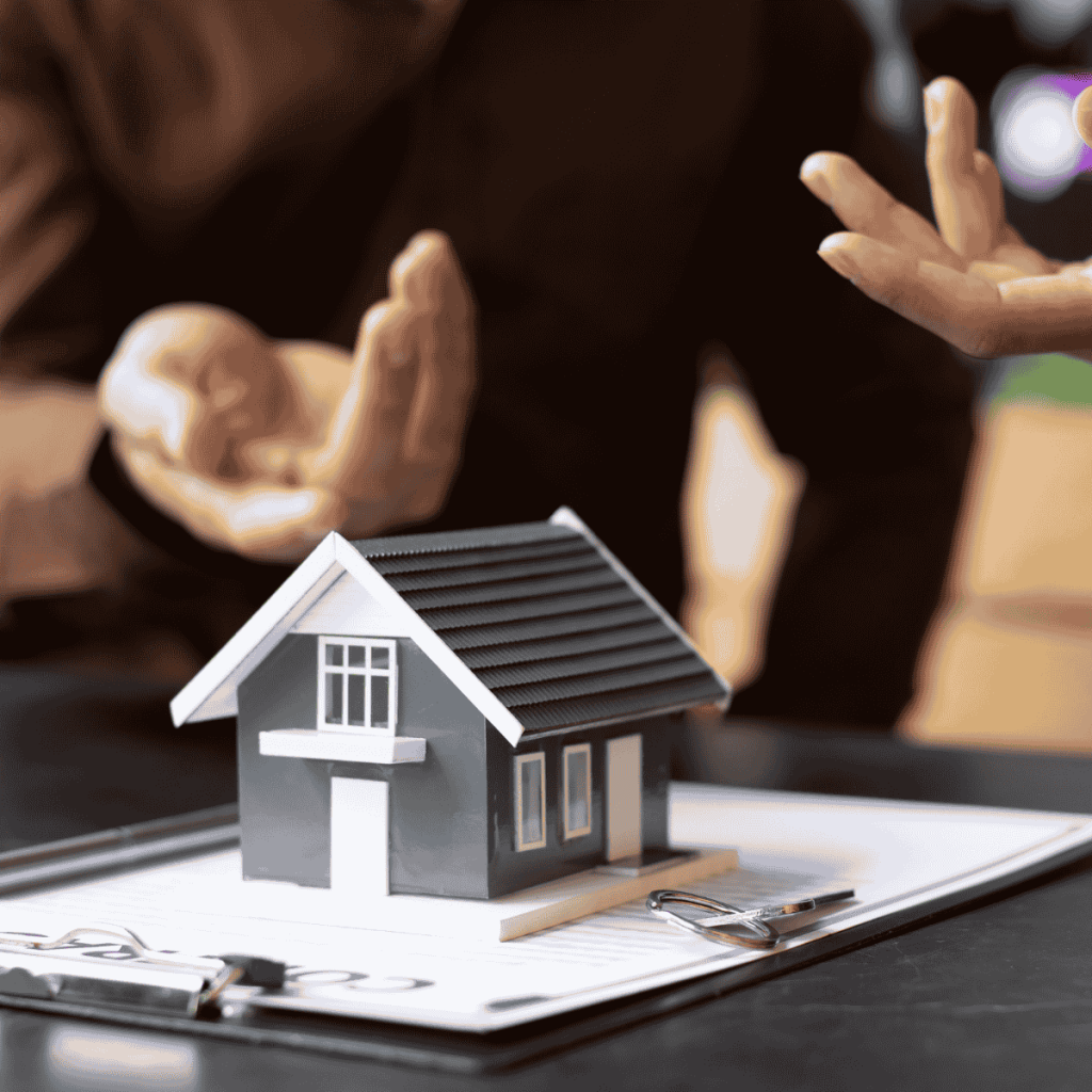Two people discussing real estate with a small house model, keys, and documents on the table.