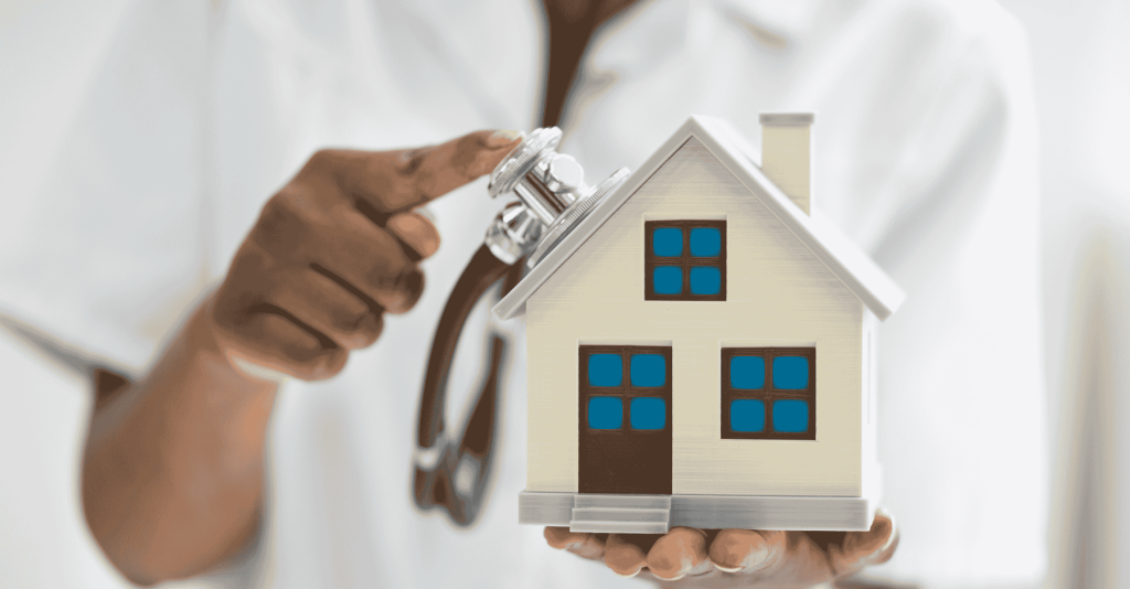 A person holding a small house model while using a stethoscope to examine it, symbolizing a home inspection.