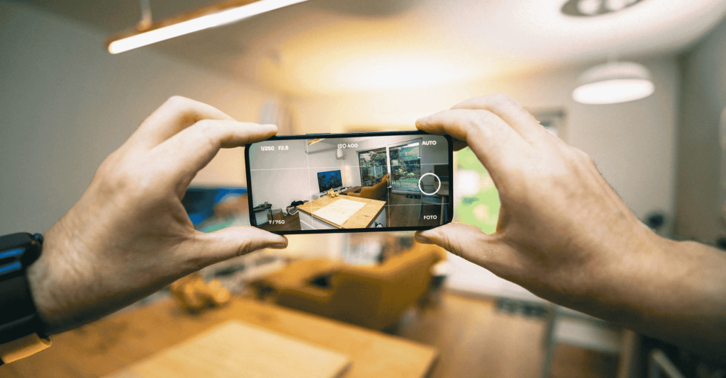 Person taking a real estate listing photo of a modern living room using a phone.