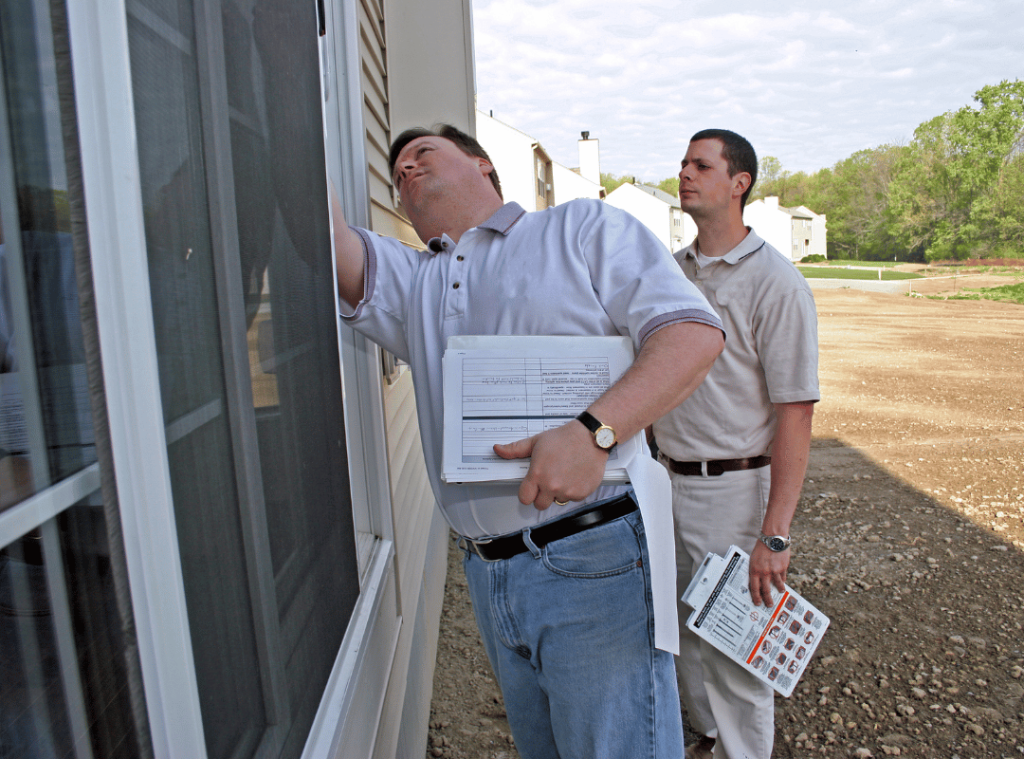 men inspecting windows and walls outside during home inspection