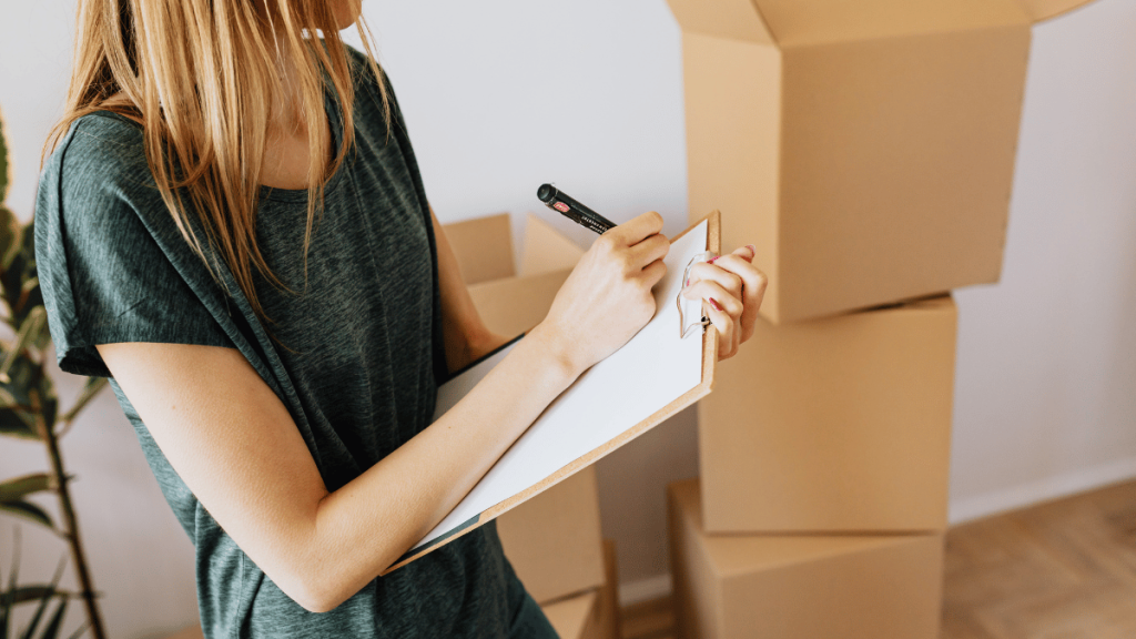 woman writing on checklist while packing up her home